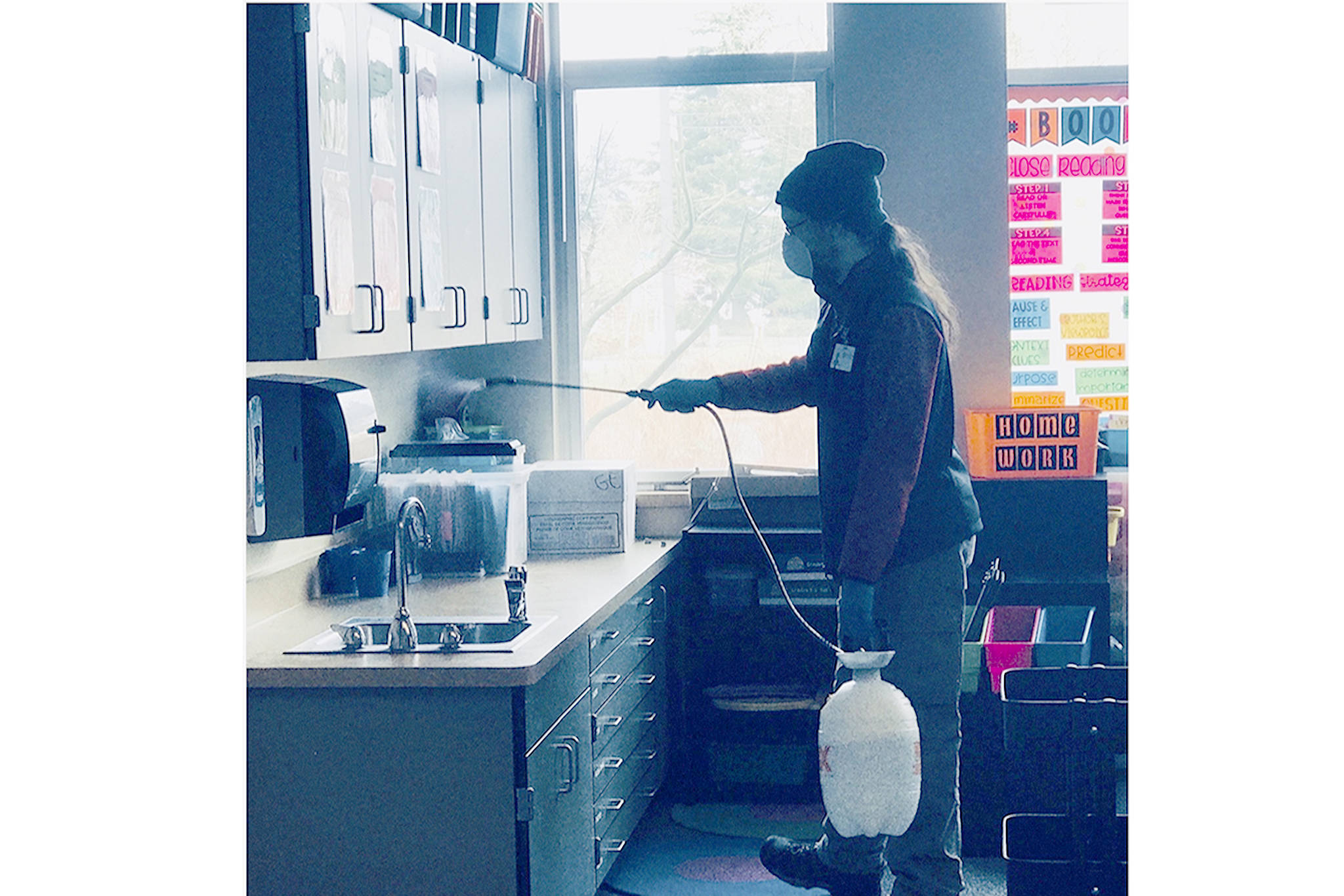 Courtesy Photo                                 A custodian sprays a surface with disinfectant. Ten minutes later the spray was wiped down. Work continued into the evening so both schools could reopen Wednesday.